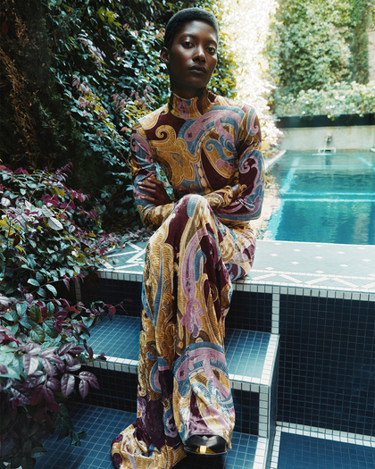 woman sitting closed to a swimming pool with a dress from the ETROxMT capsule 