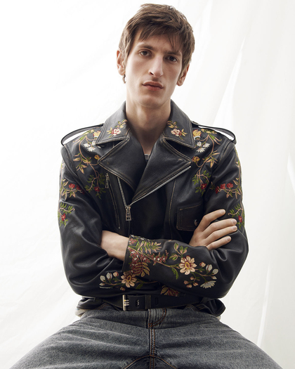Young man wearing a leather jacket with flowes design - link to man's coat 