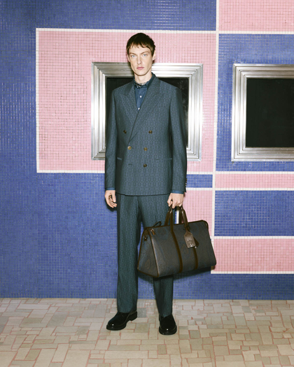 Model dressed in a tailored Etro double-breasted suit, paired with a sleek travel bag