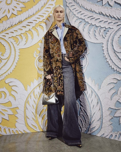 Model wearing Etro floral paisley velvet coat, holding a laminated vela bag