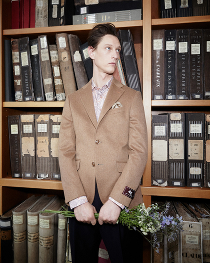 Man wearing a cachemere blazer standing in front of a library