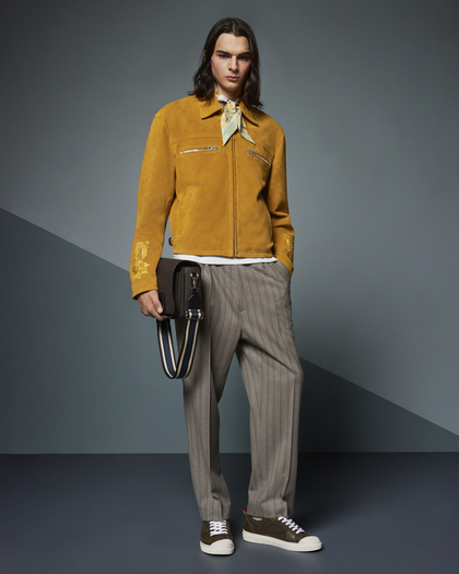 young man standing still wearing a SUEDE JACKET WITH EMBROIDERY and STRIPED TROUSERS WITH PLEATS