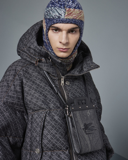 Model wearing Etro: a geometric patterned hooded jacket, a multicolored knit balaclava, and a small crossbody bag with a paisley design.