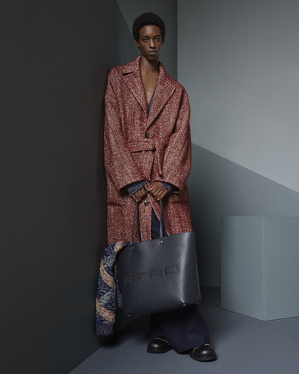 Model wearing an oversized red textured coat, wide-leg trousers, and holding a large black Etro tote bag.