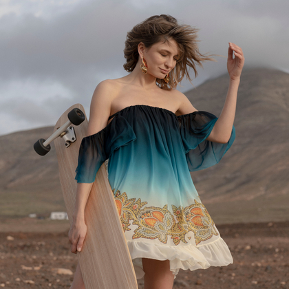 Girl with skateboard in the desert, wearing dangling earrings and silk mini dress with dropped shoulders shaded Paisley