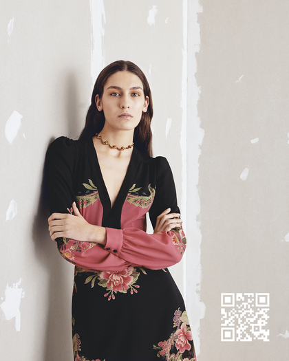 A girl leaning against the wall wearing a floral printed dress 