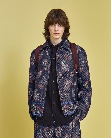 Young man wearing a jacket with geometric quilting, placed Paisley print and cornice detail. link to man's coat 