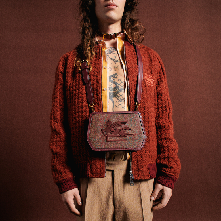 Model posing with Etro shoulder bag with Paisley patterns on an orange background 