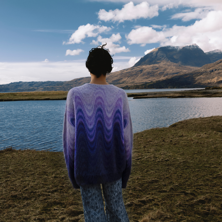 Boy-shoulders-with-mountains-and-lake-wearing wool jumper in shaded purple waves and jacquard jeans