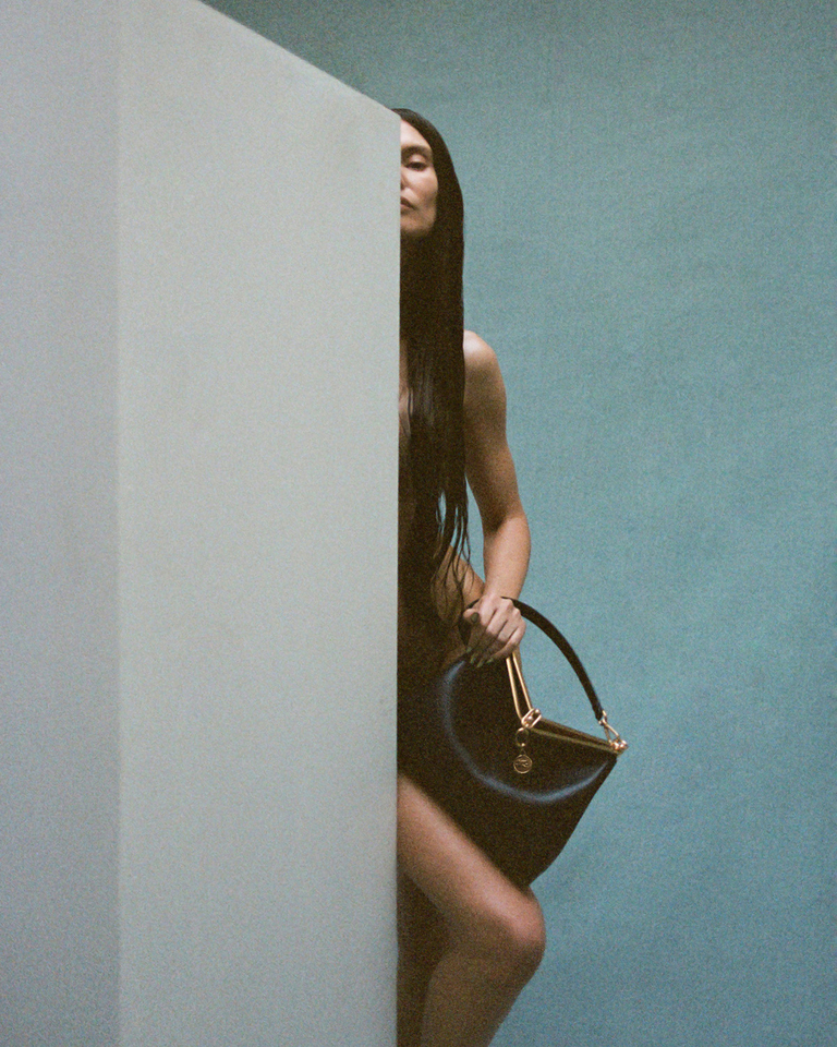 Bianca Balti holding an Etro Vela Bag behind a door