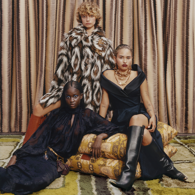 Three models sitting on maxi pillows, wearing clothes from the PE24_ Holiday collection.