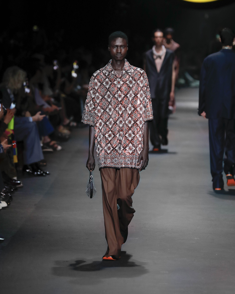 Model with geometrically patterned shirt, long brown trousers and black handbag Etro Spring Summer collection 2024 fashion show