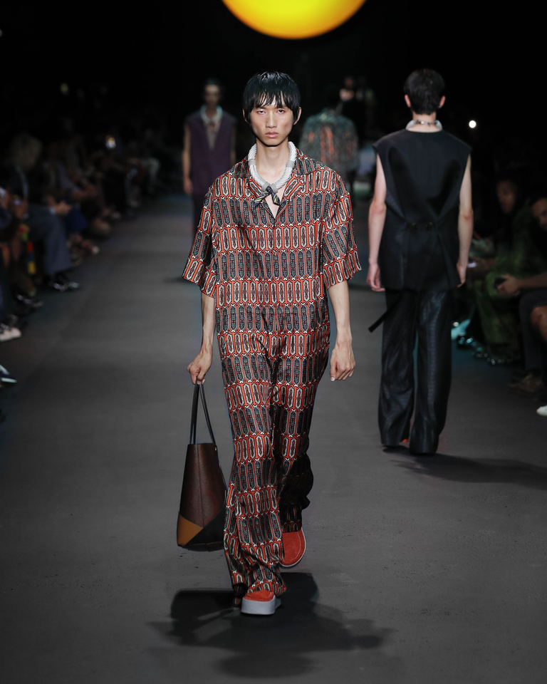 Model with red suit with geometric patterns, white necklace and brown handbag Etro Spring Summer collection 2024 fashion show
