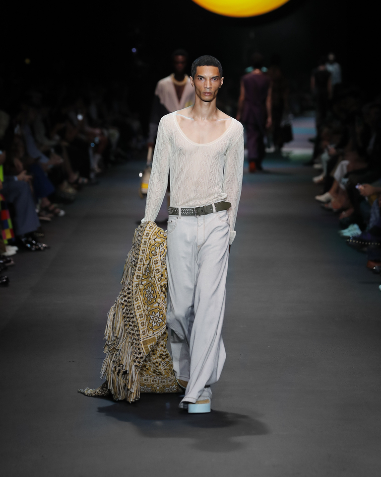Model with transparent long-sleeved sweater, white long trousers and golden poncho Etro Spring Summer collection 2024 fashion show