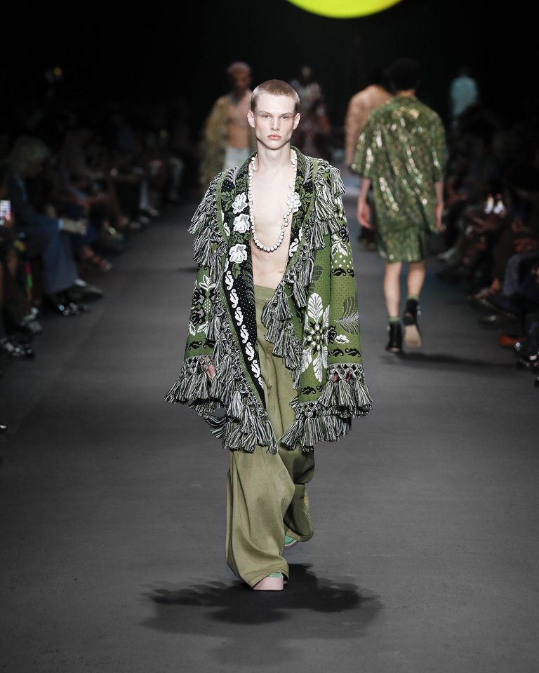 Model with white necklace, green poncho with floral patterns and long green trousers Etro Spring Summer collection 2024 fashion show